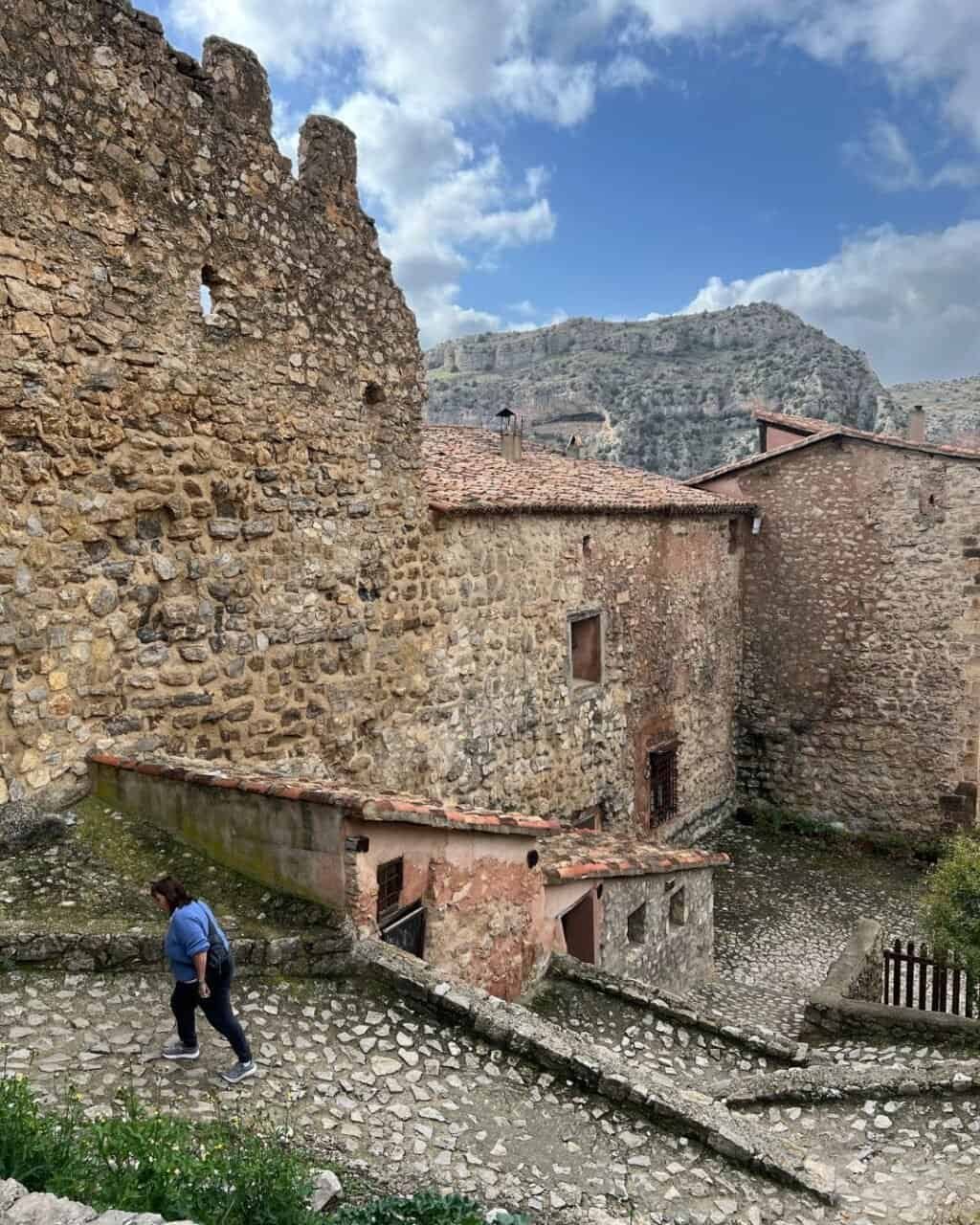 a woman walking up the steep cobblestone lanes in albarracin