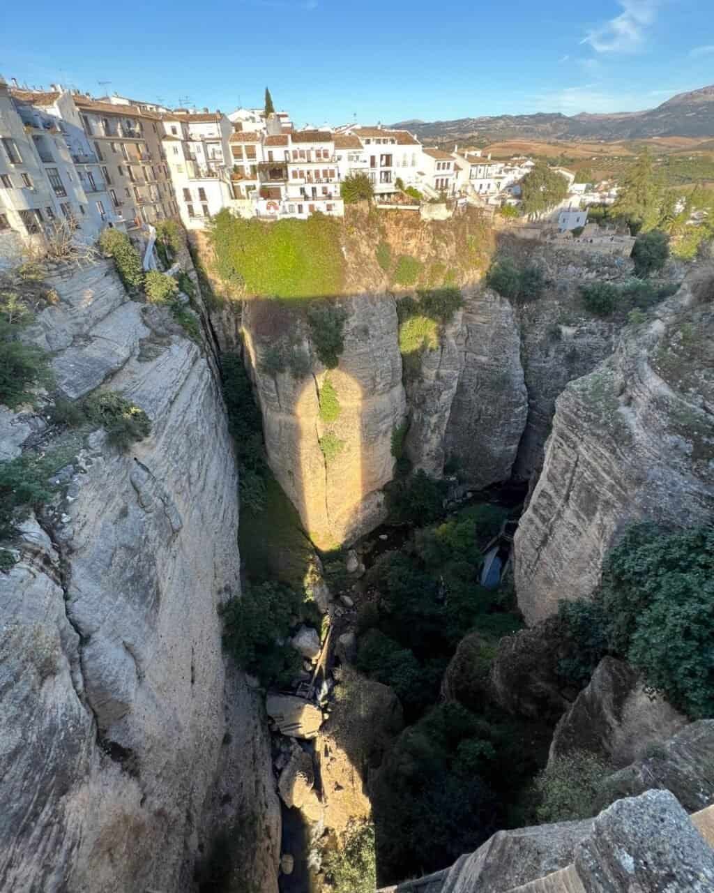 the setting sun creates beautiful shadows of the ronda bridge against the gorge