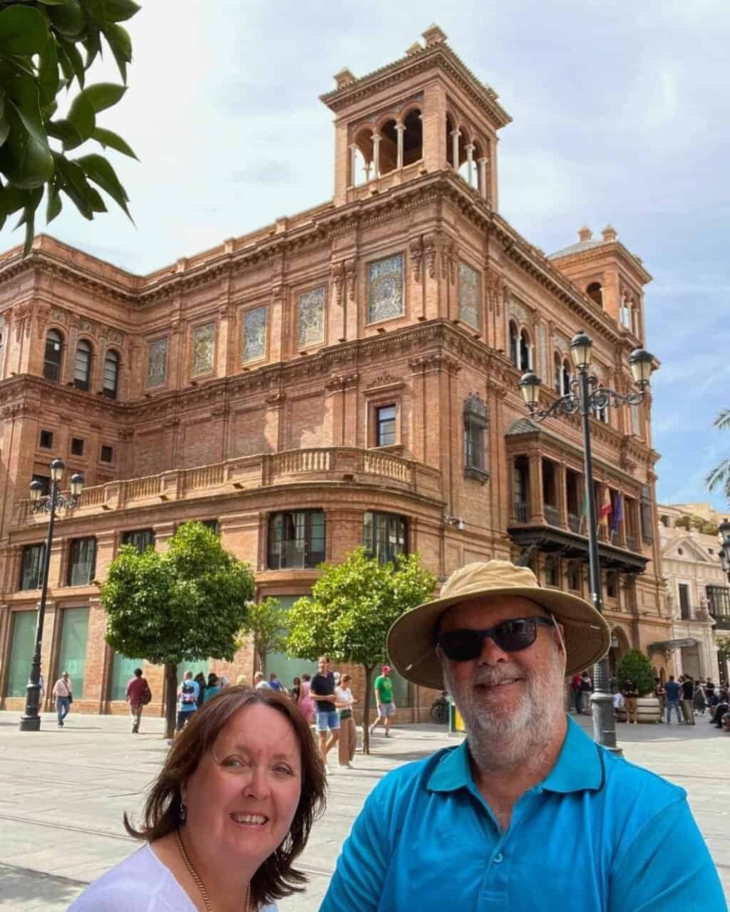couple stading in front of a beautiful building in sevilla