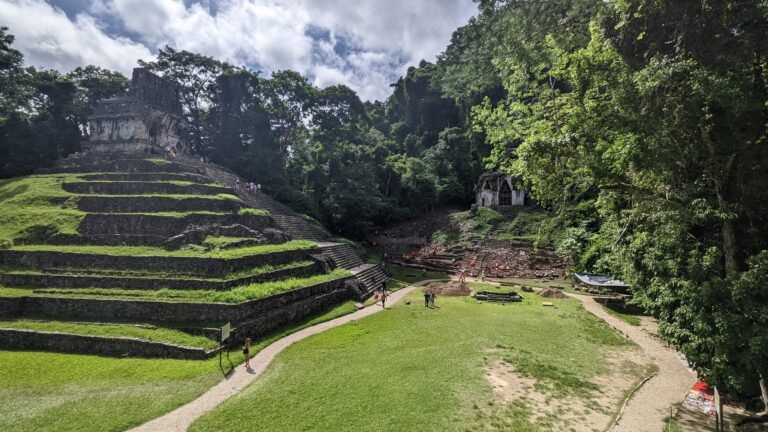 looking across green grass to one of the pyramids in the Palenque Mayan city