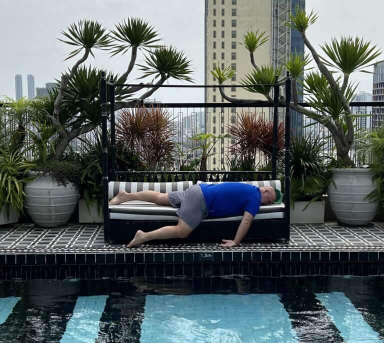 exhausted person laying on a daybed next to a pool